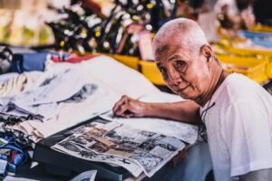 elderly man reading a newspaper at a market stall